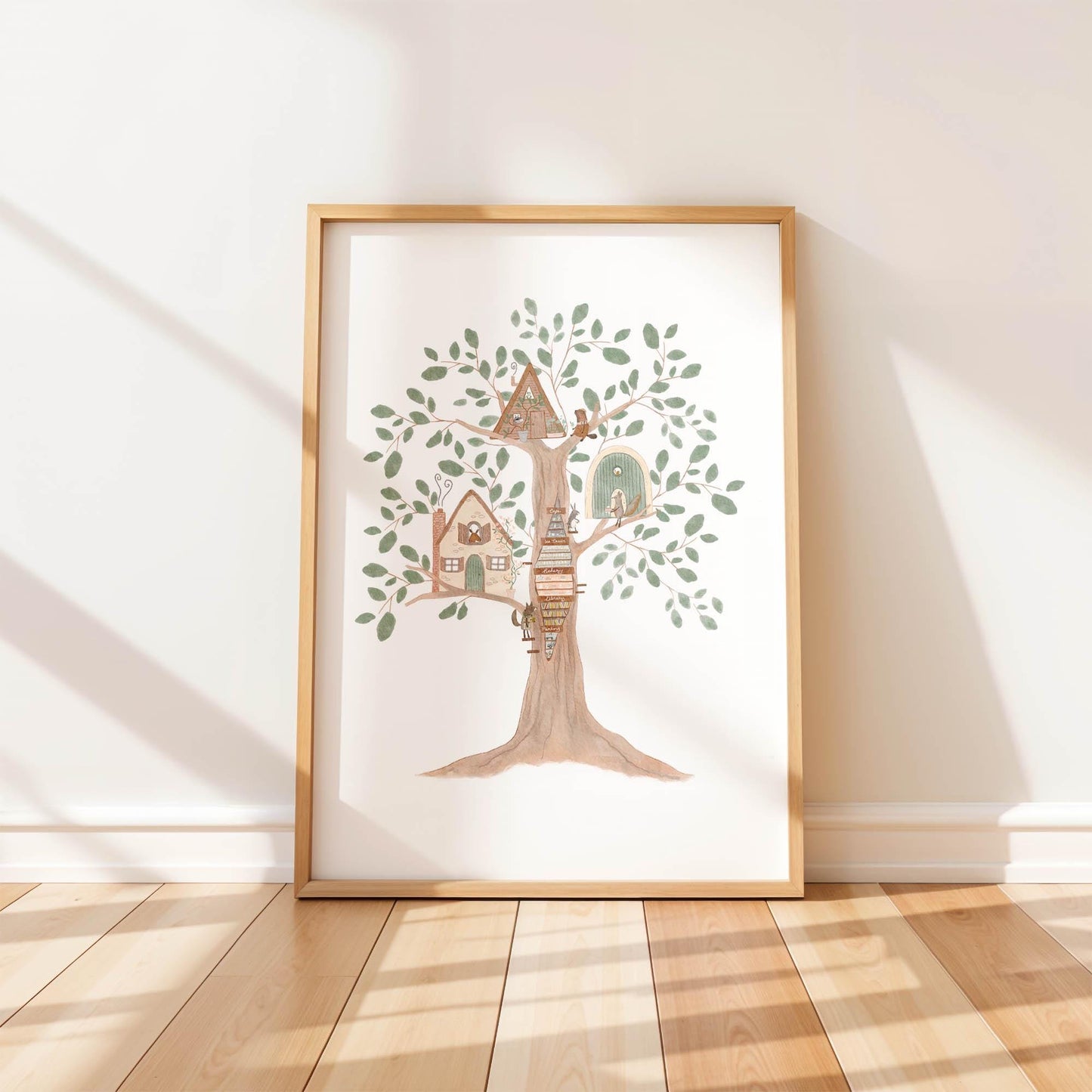 A single framed art print leaning against a white wall, featuring a whimsical watercolor illustration of a large tree filled with tiny, magical houses for woodland animals.