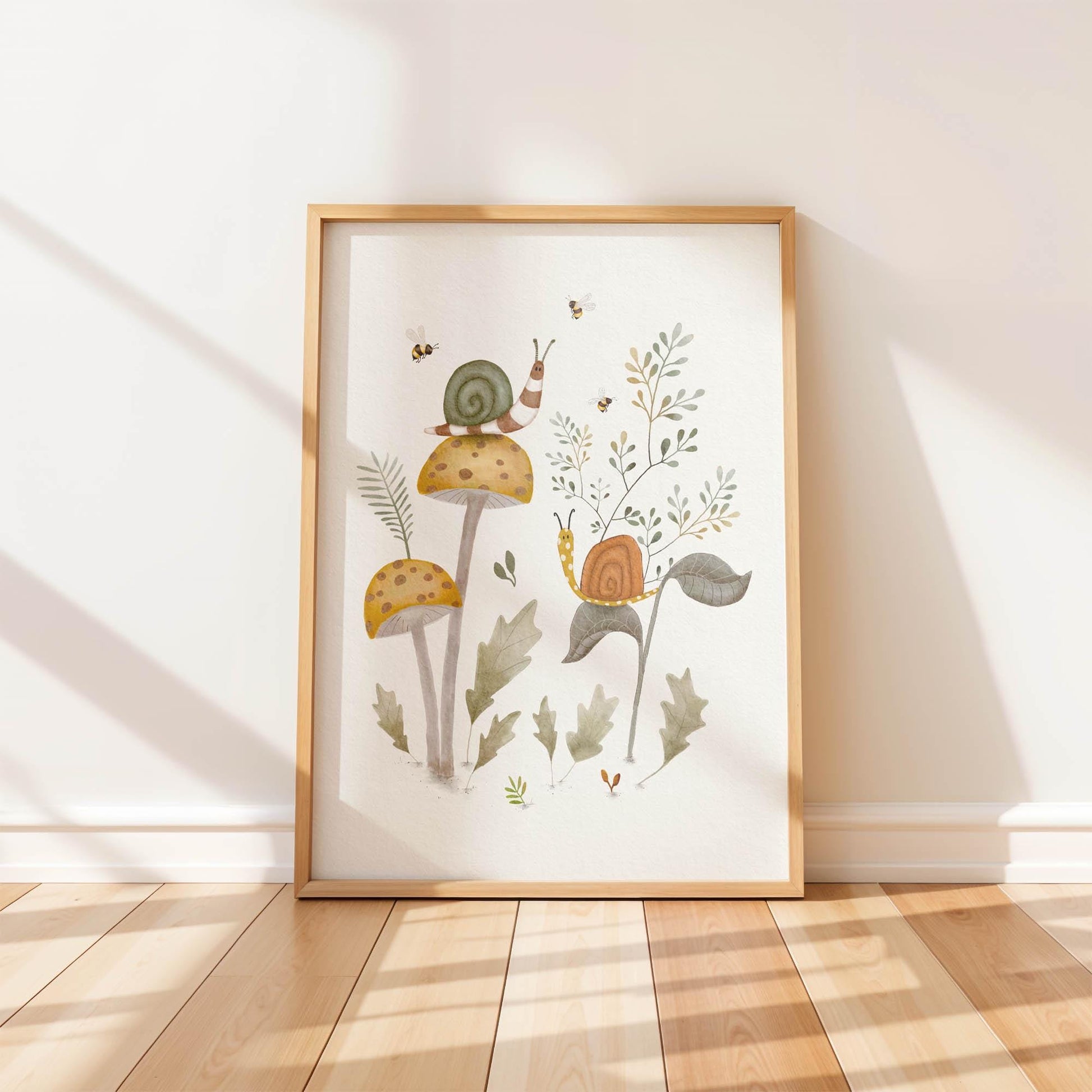 Snail on mushroom art print in a light wood frame on a wood floor, showing two snails on mushrooms and leafy plants, with small bees flying around.
